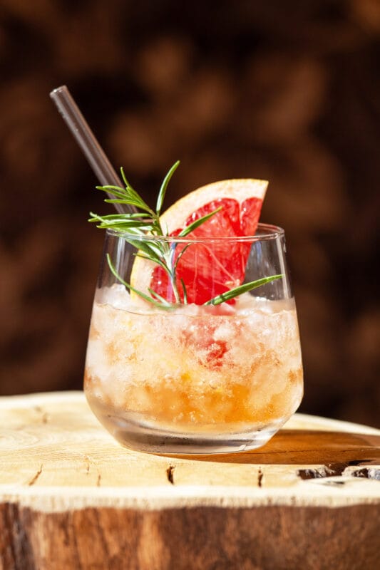 La Cascara Spritz Ready To Drink - fertig serviert in einem Glas mit Eiswürfeln, Rosmarin und Grapefruit