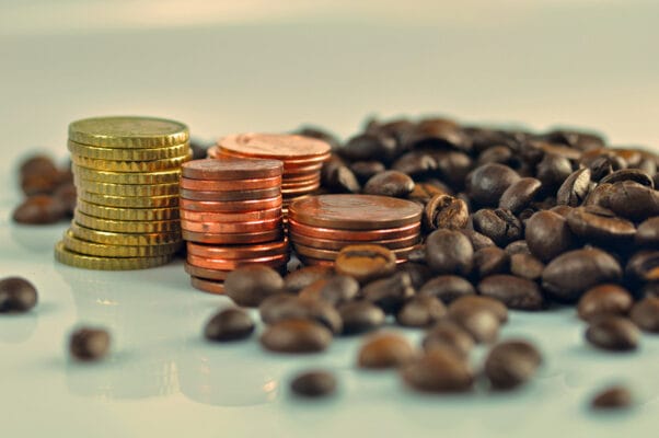 Münzen und Kaffeebohnen als Symbolbild für steigende Kaffeepreise 2025